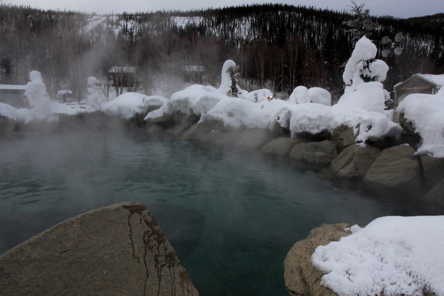 Steam rising off the outdoor rock pool at Chena Hot Springs, its boulders heaped with snow